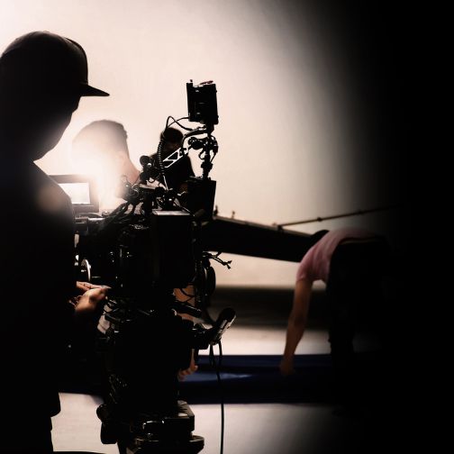 Fotografija prikazuje snemalca s kamero, zunanjega strokovnega sodelavca za video produkcijo